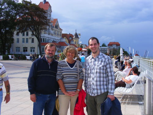 drei Personen stehen auf einer Strandpromenade