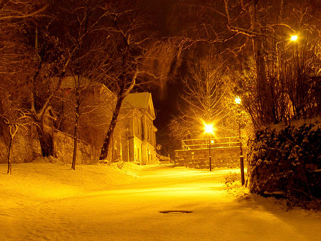 Eine verschneite Straße im Lichte gelblicher Laternen
